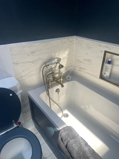 Navy and marble bathroom with panelled bath and traditional brass mixer tap