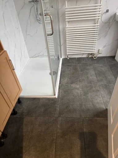 Marble-tiled walk-in shower enclosure with grey porcelain floor