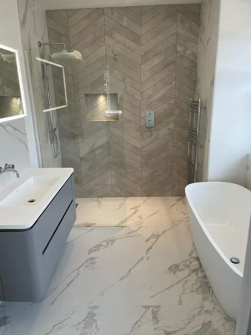 Bathroom with chevron-tiled walk-in shower, marble floor and freestanding bath